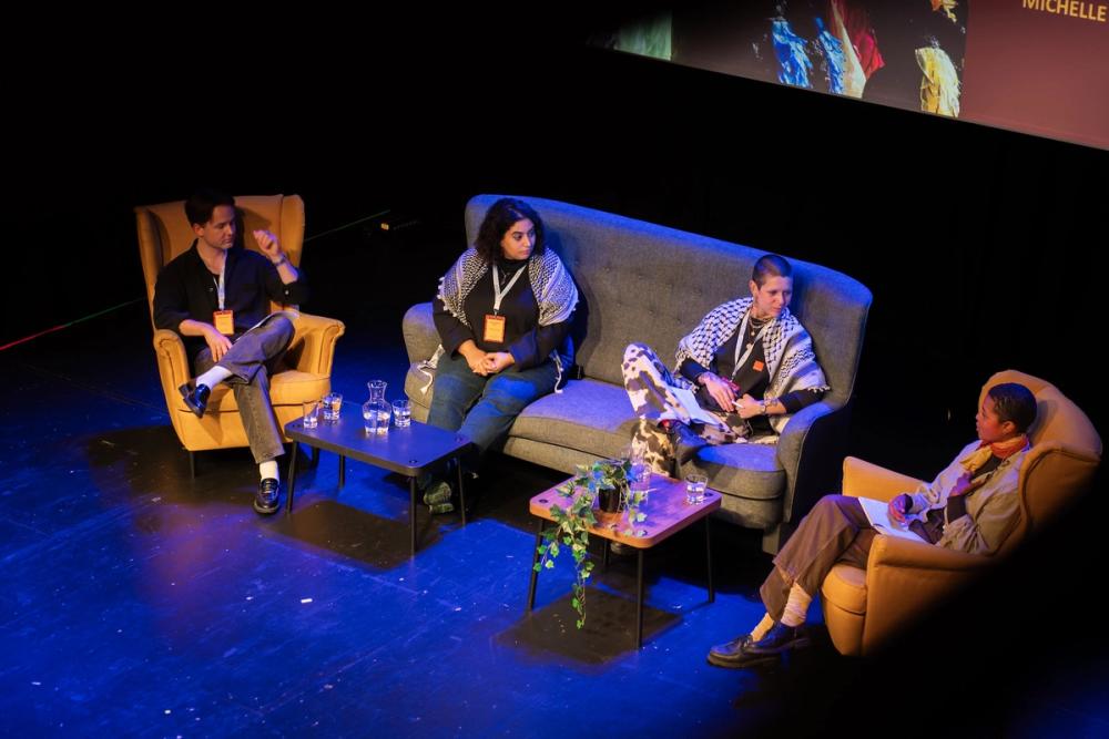 Fire personer sitter i sofa og stoler på en scene og har en debatt.
