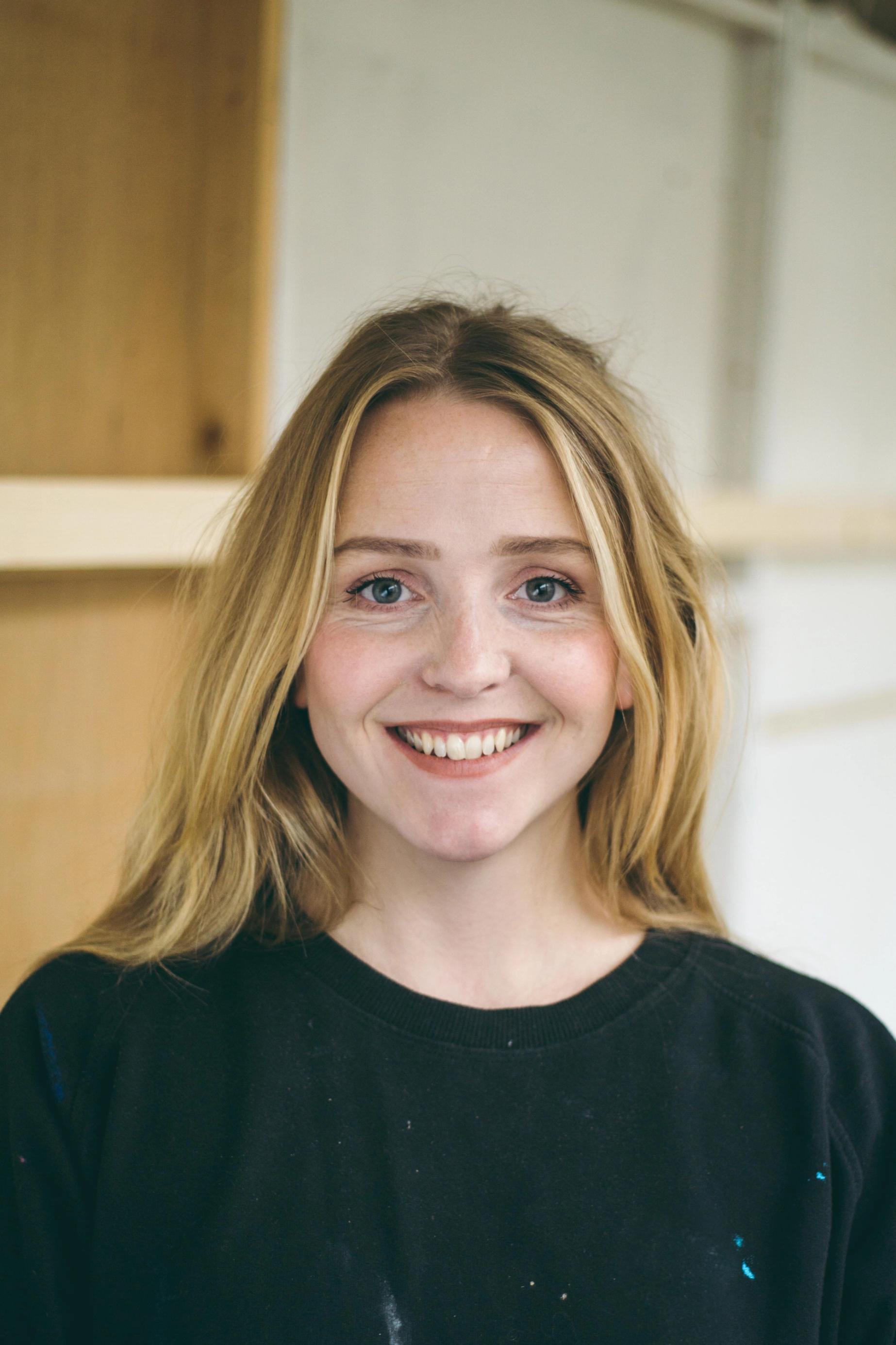 En lyshåret kvinne smiler til kamera