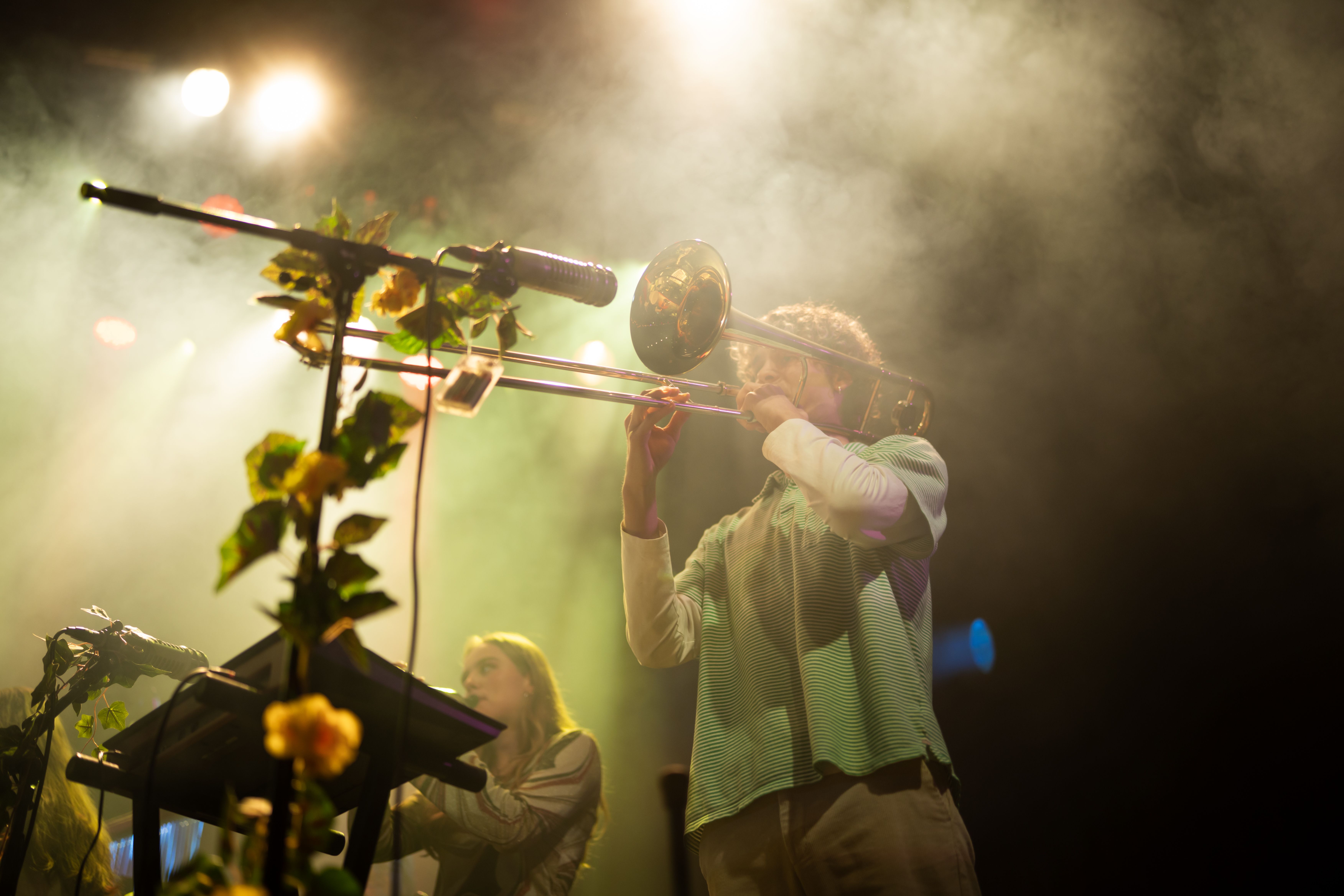En mann i grønn skjorte spille trombone på en lyssatt scene