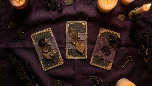 Kolme tarot-korttia levitettynä tummalle liinalle kynttilänvalossa