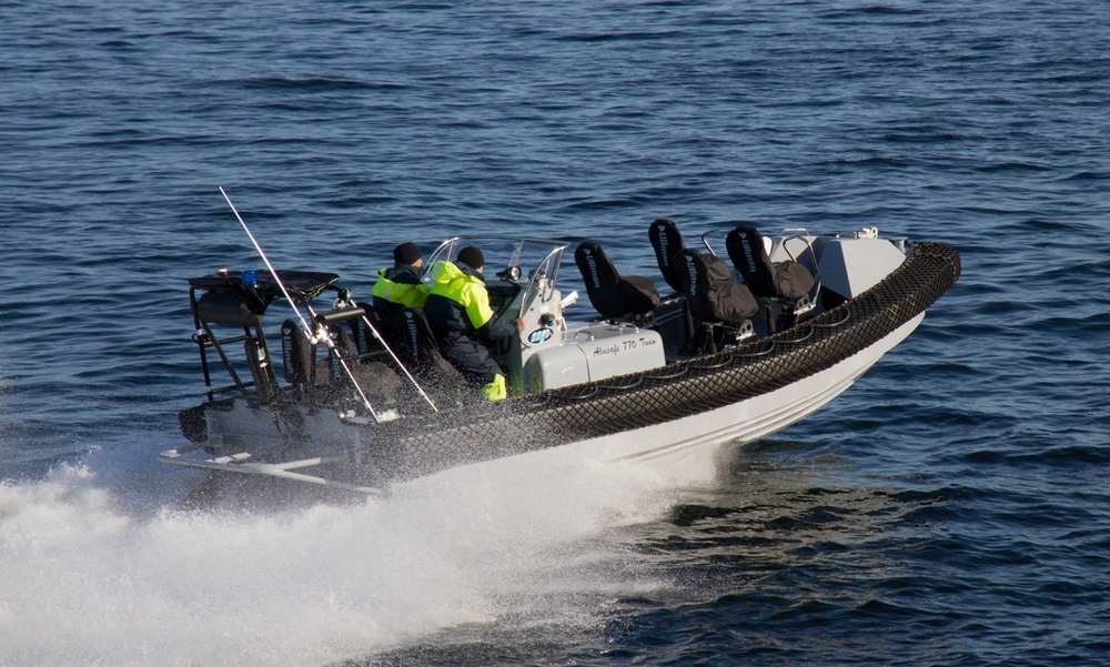 Redningsbåt kjører på sjøen med to personer i gule verneklær