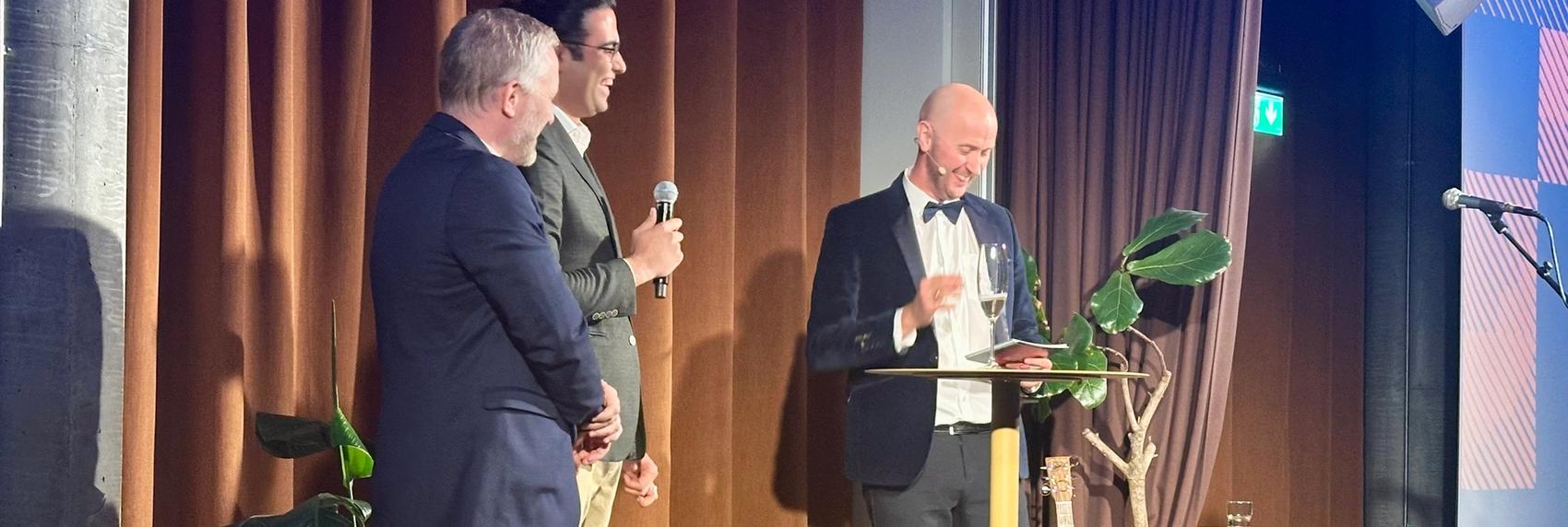 Tre menn i dress på en scene