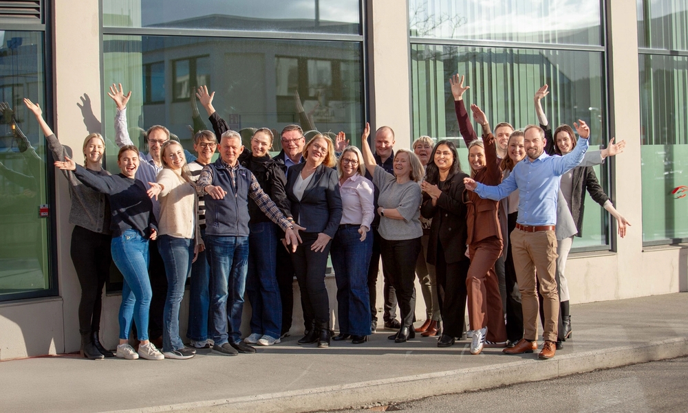 En gruppe mennesker jubler med hendene i været, utendørs.