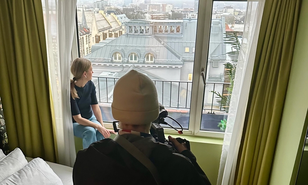 Kvinne ser ut over en storby fra et vindu på et hotellrom