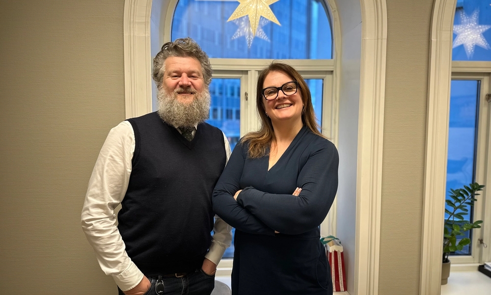 To personer står foran vindu med julestjerne