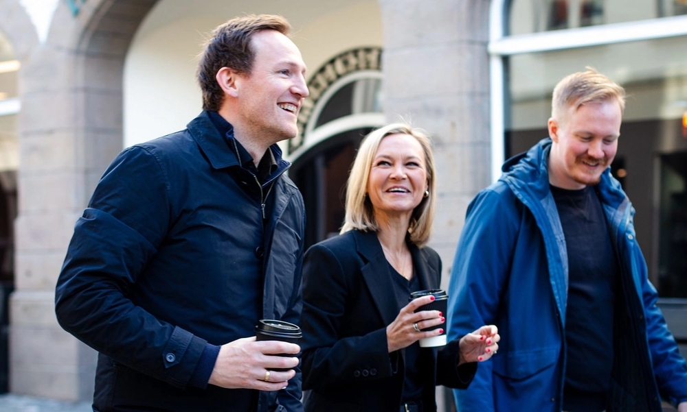 Tre personer går i en gate og prater sammen