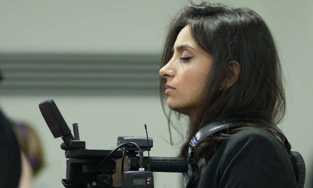 Kvinne fra siden holder kamera i hendene