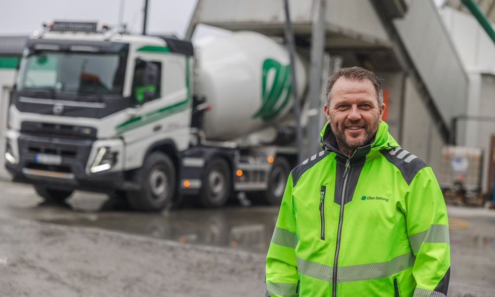 Mann i gul jakke står foran en betongbil.