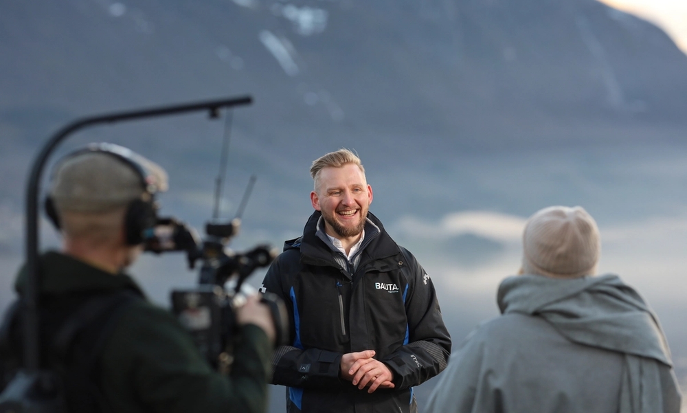 Mann blir intervjuet av kvinne og person med kamera