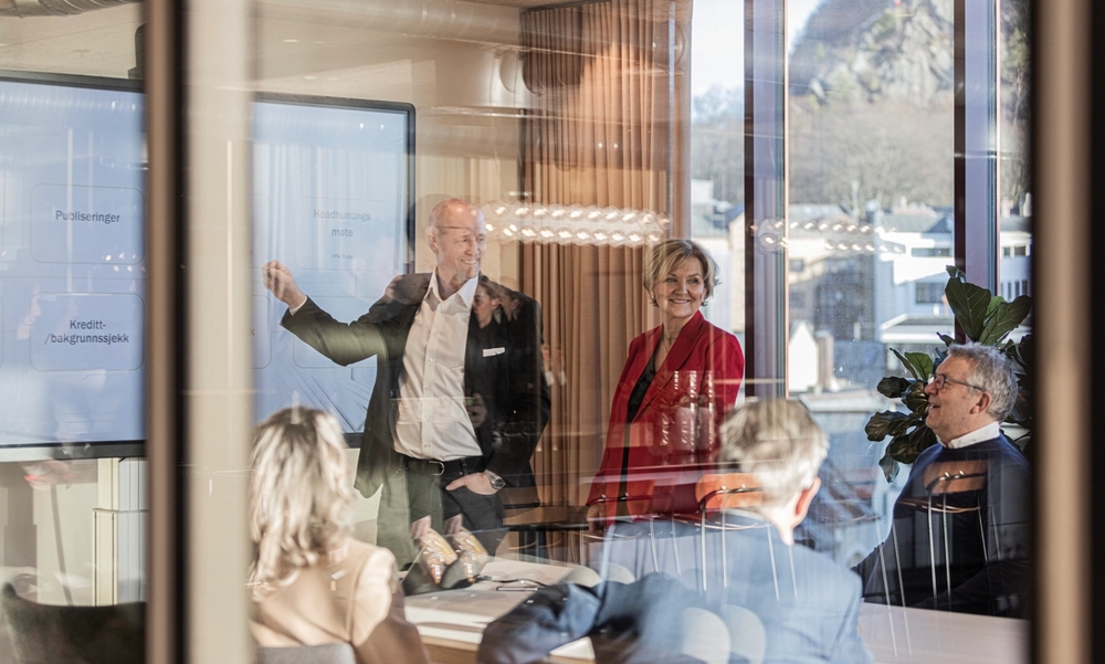 To personer presenterer noe fra en skjerm i et møte.