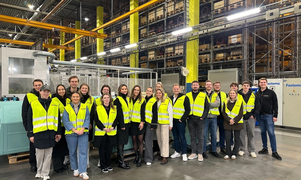 Personer som står samlet i en fabrikk.