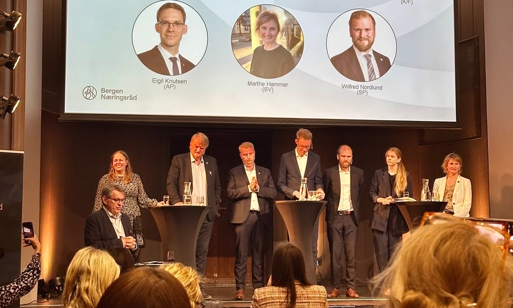 Syv politikere på en scene, klare for debatt.