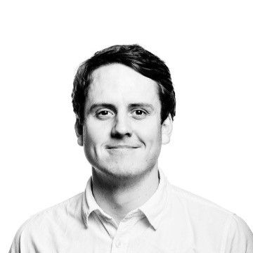 Svart/hvitt portrettbilde av mann som smiler.