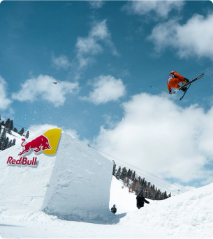 Skier jumping off a jump with a Red Bull logo