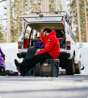 Snowboardeur assis sur une glacière YETI