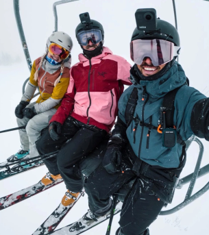 Skiers on a chairlift with GoPros mounted to their helmets