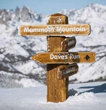 A wooden sign buried almost to the top by snow. Signs read Mammoth Mountain and Dave's Run.