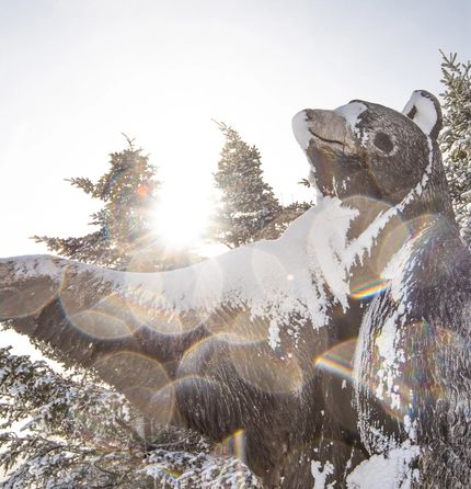 A bear statue covered in snow at the top of a mountain