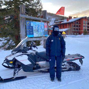 Person in winter gear standing in front of a snowmobile