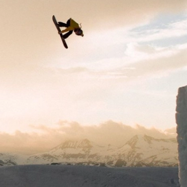 snowboarder doing a trick off a terrain park jump