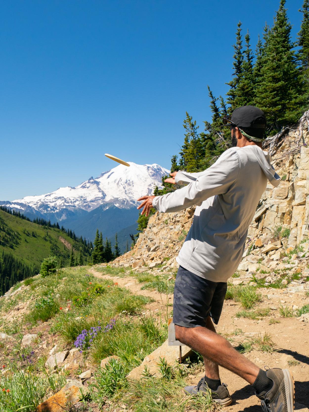 Person throwing a frisbee during a disc golf game in the mountains