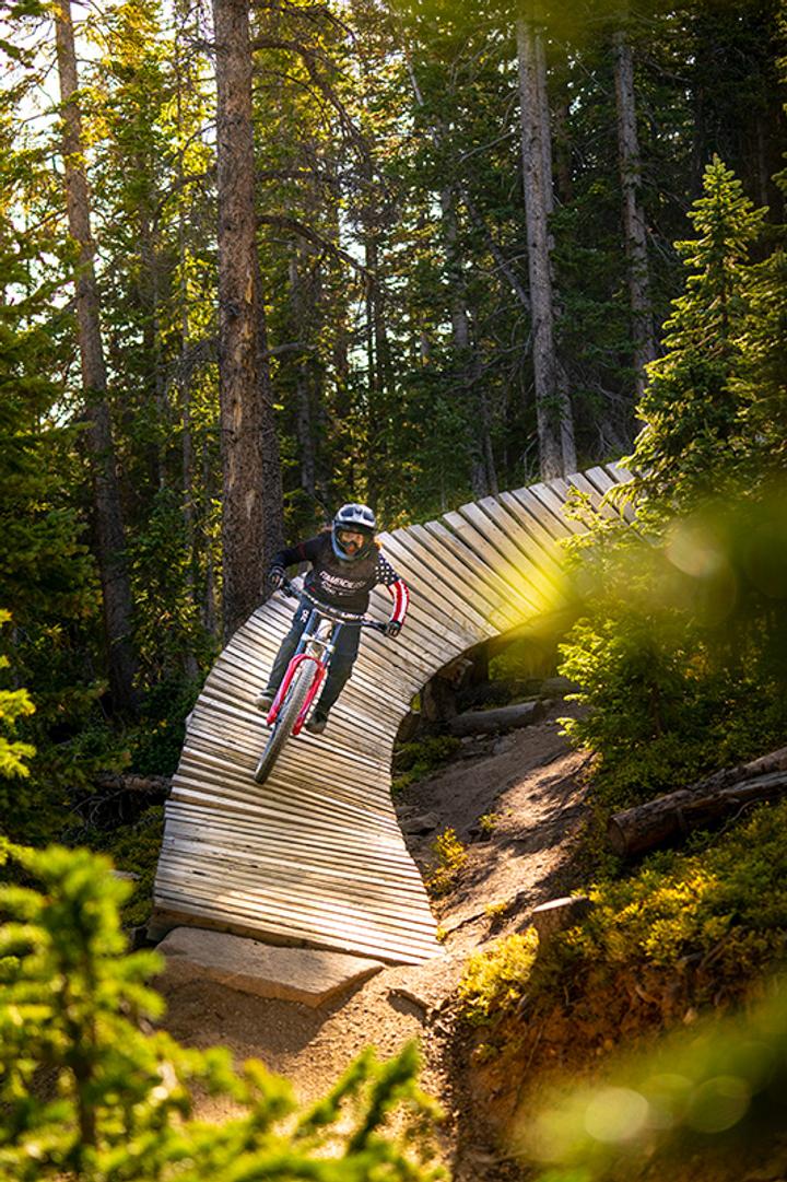 Person riding a mountain bike over wooden trail features
