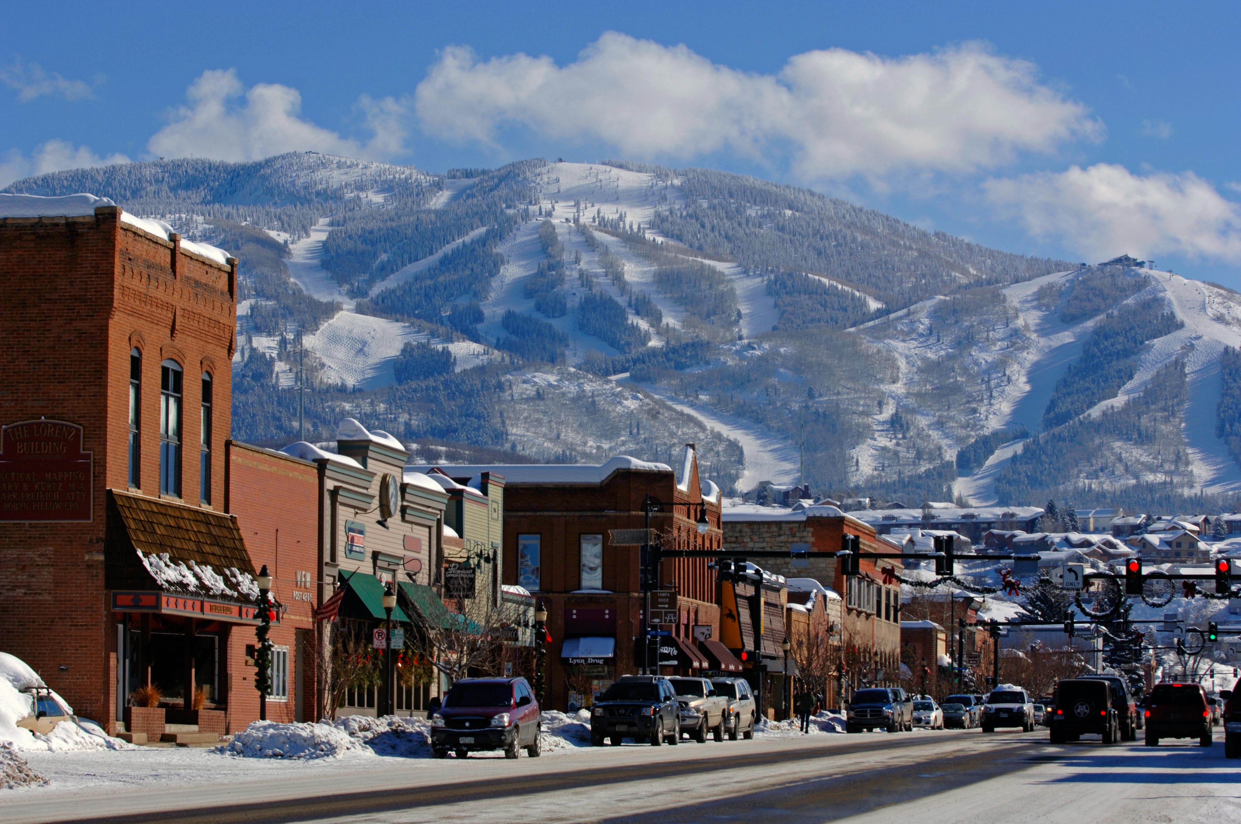 Scenic view of a mountain town with a ski resort in the distance