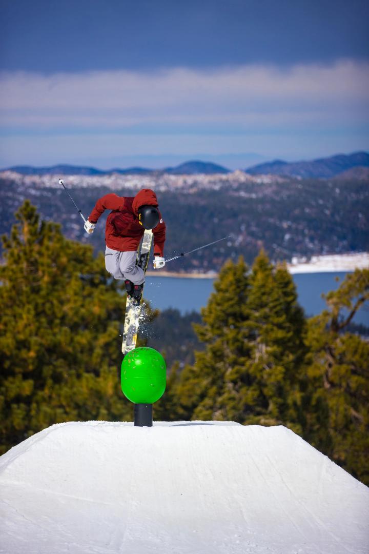 A skier doing a trick off a feature at a terrain park