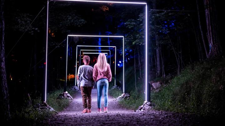 Two people viewing the immersive neon light experience as it illuminates the night.