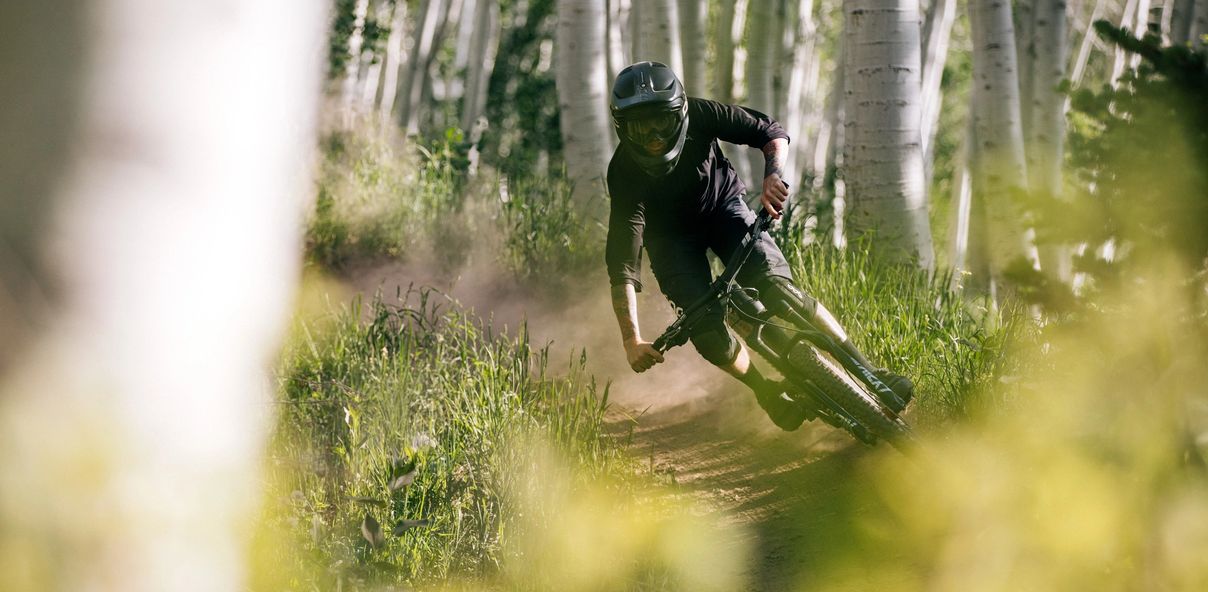 Person riding a mountain bike on a dirt trail through the trees