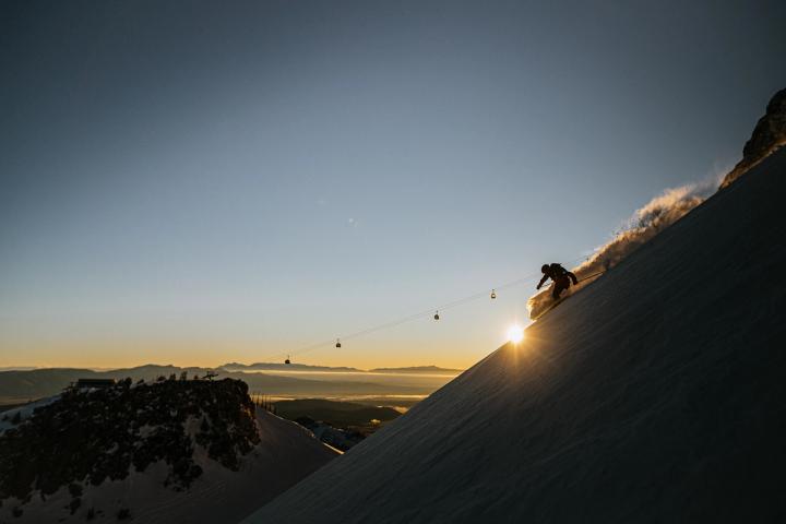 Person skiing down a run at sunset