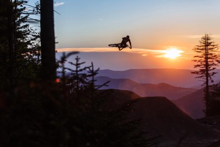 Person jumping in the air on a bike at sunset