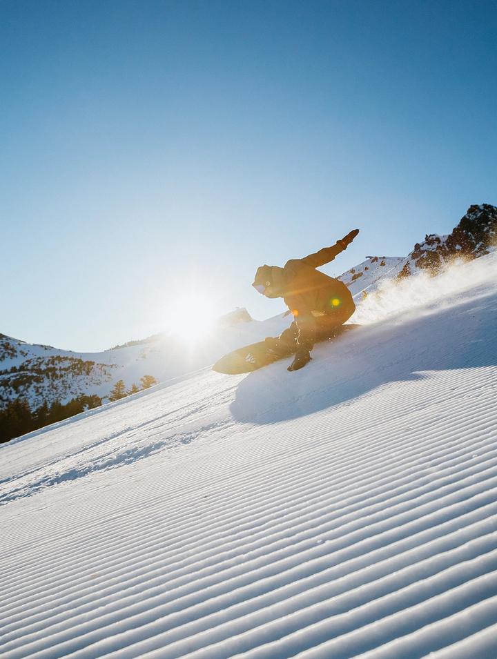 Snowboarder riding down a groomed run