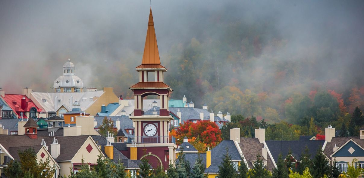 A clocktower standing tall among colorful buildings on a foggy day