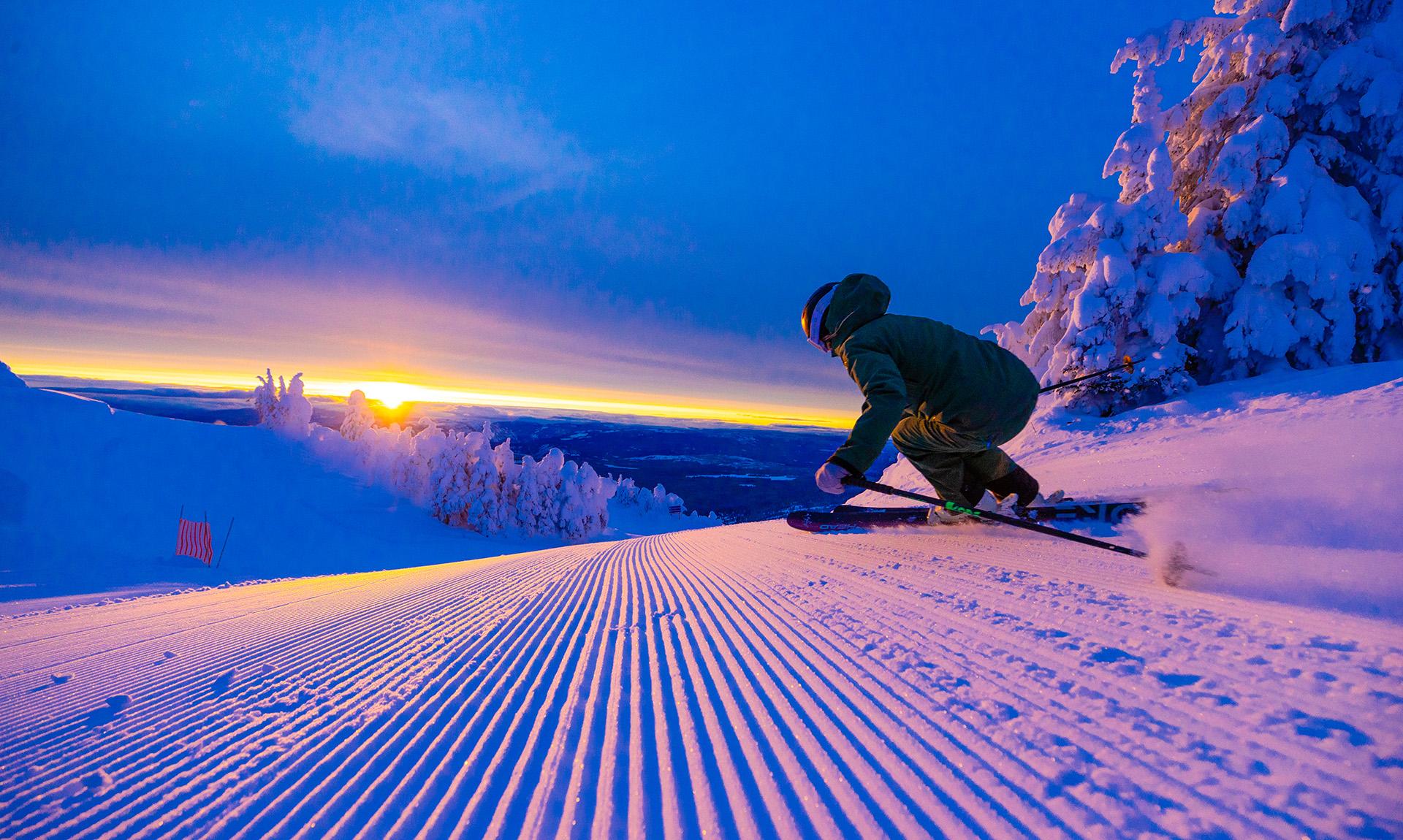Skier on a groomed run at sunrise