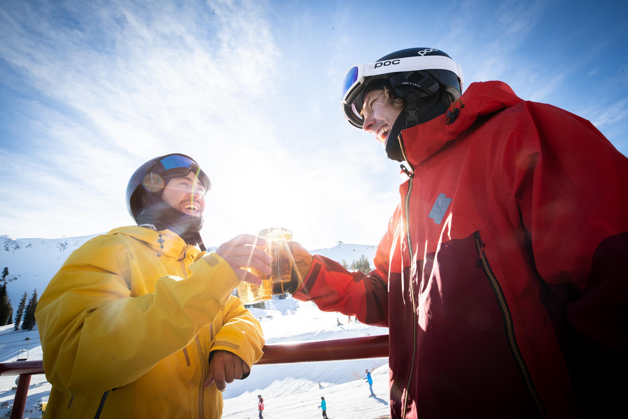 Two people in ski gear toasting beers