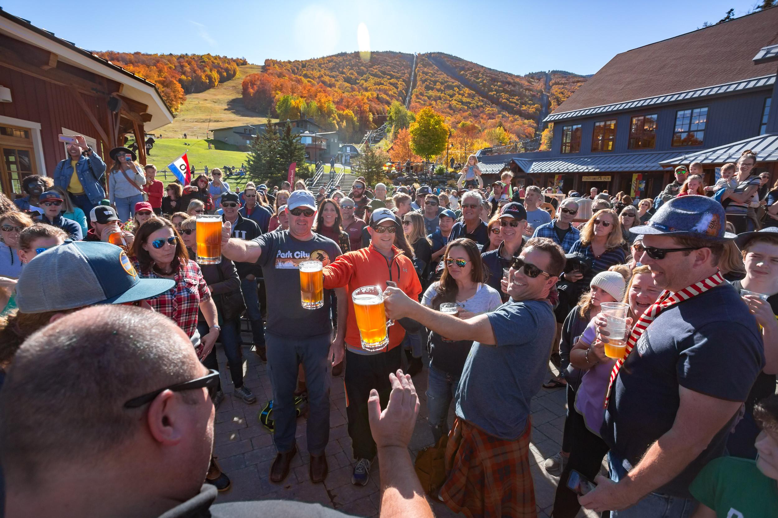 Crowd of people toasting full glasses of beer at a autumn festival