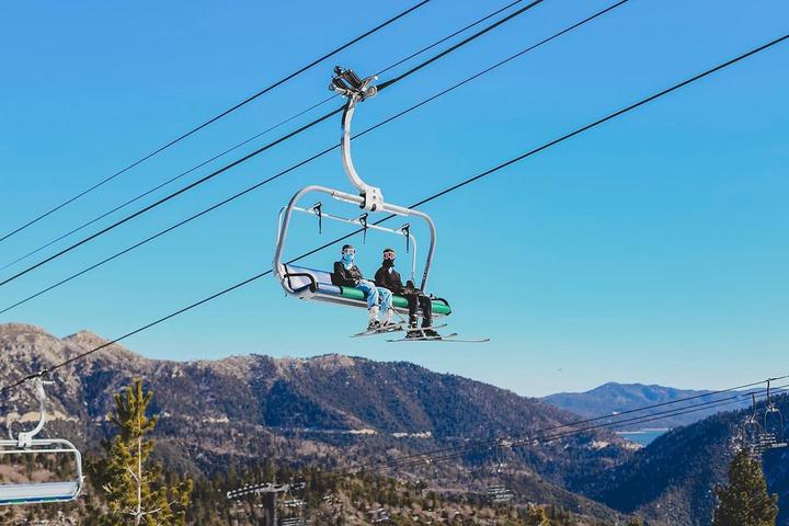 Two skiers sitting on a ski lift on a blue sky day