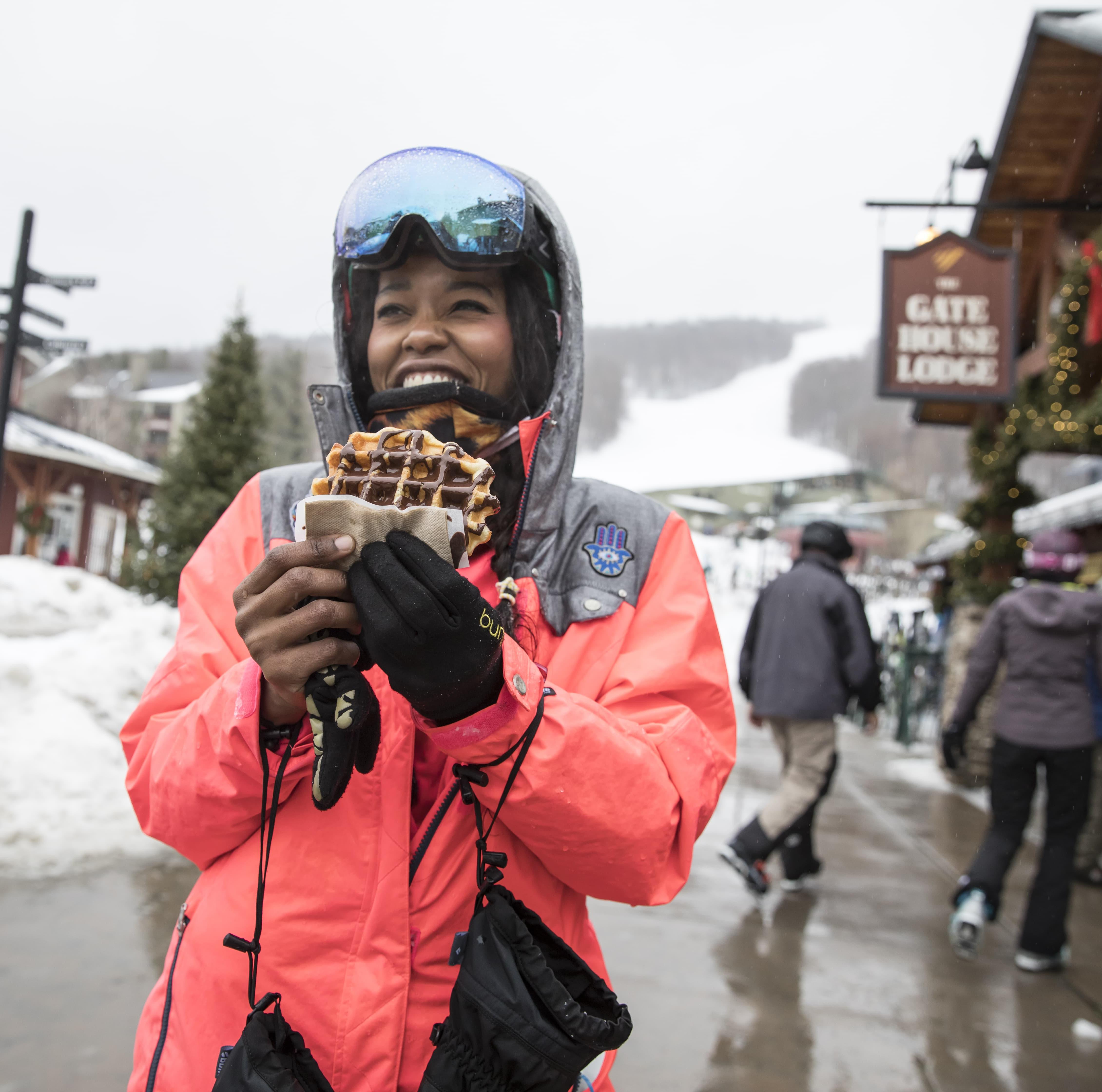 Person in ski gear holding a waffle and smiling