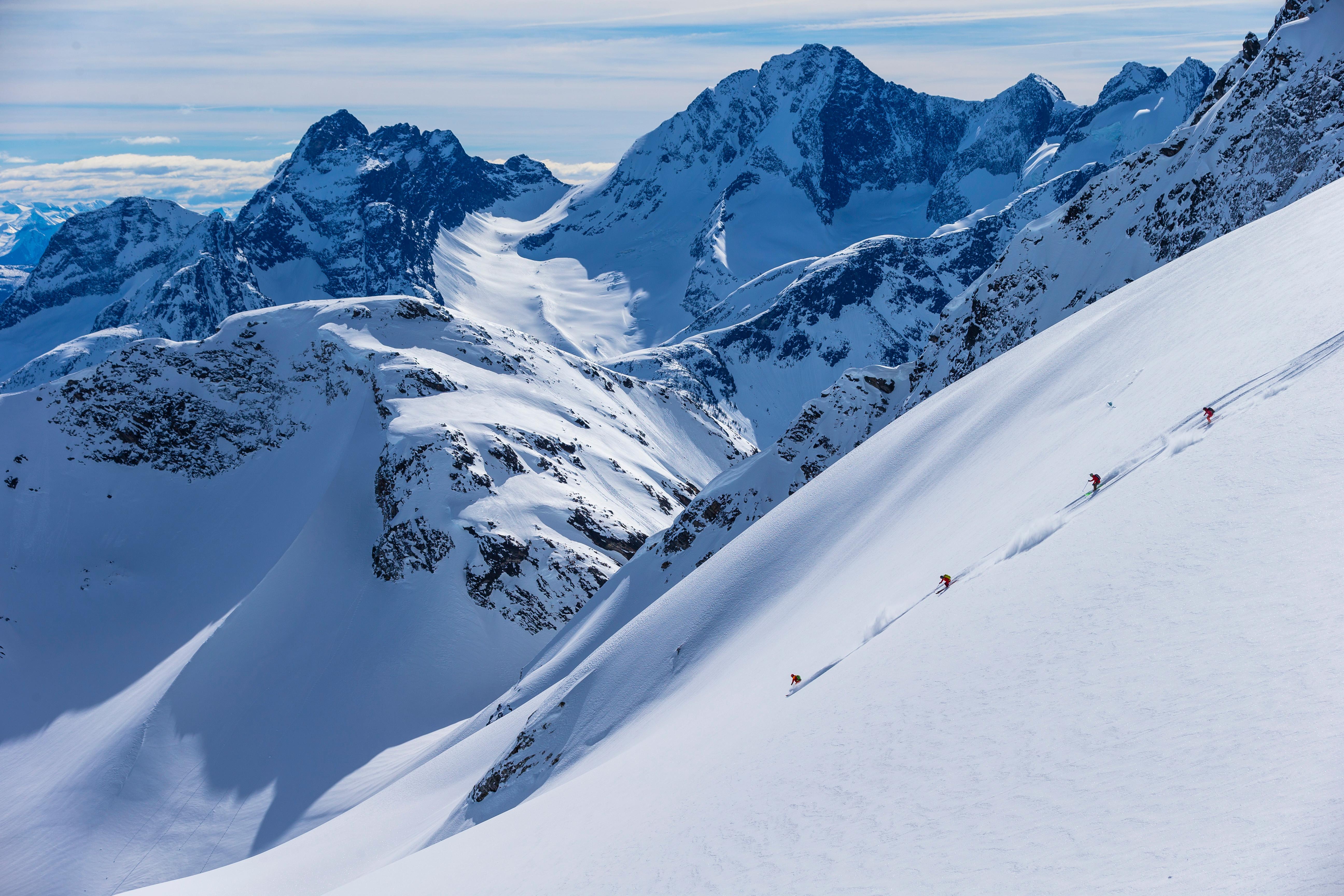 a line of skiers going through untouched powder
