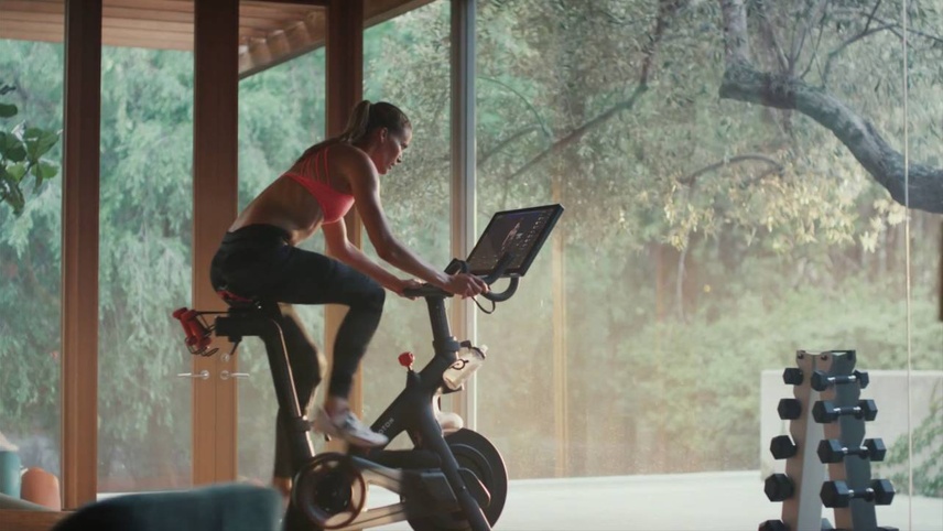 Image of woman on peloton exercise bike in a home gym.