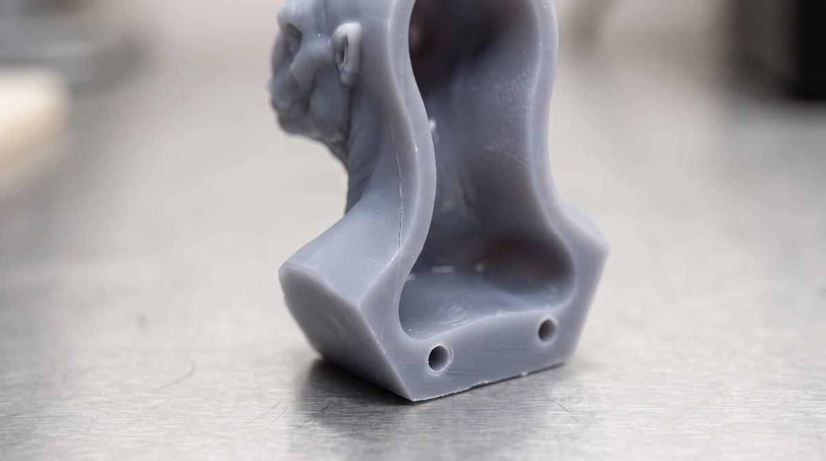 A hollow resin model sliced open showing drain holes near the base and a fine hairline crack along one seam