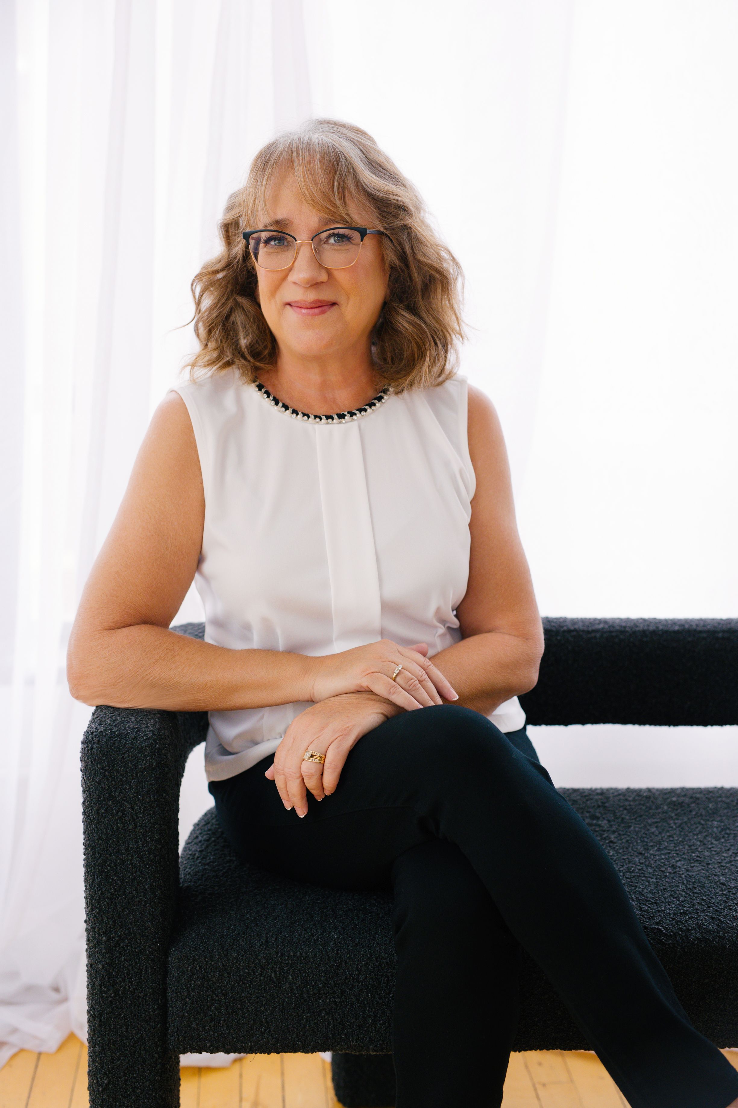 Portrait of studio owner in a white blouds on a black bench
