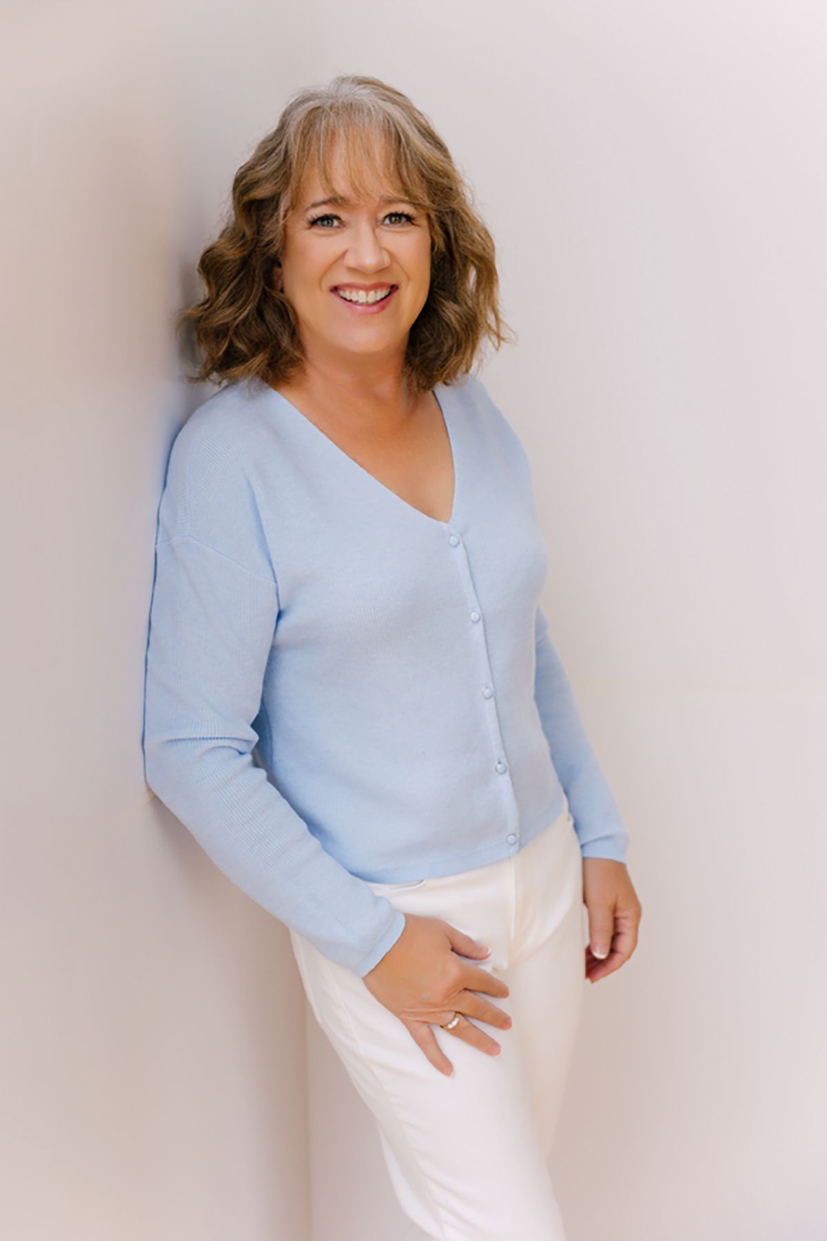 Photography studio owner in a blue sweater on a white background