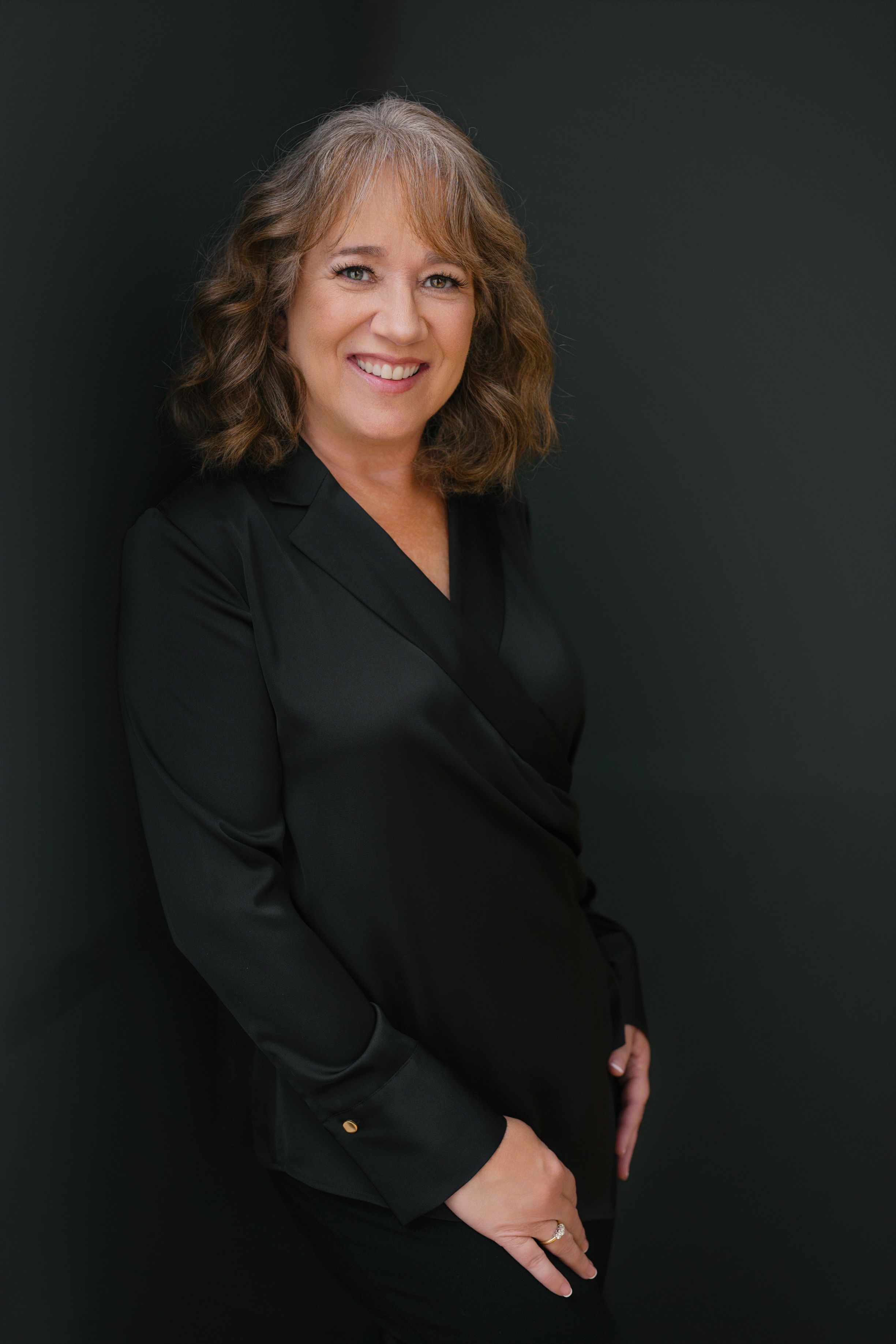 Studio owner of Coola Creative in a black blouse on a black background