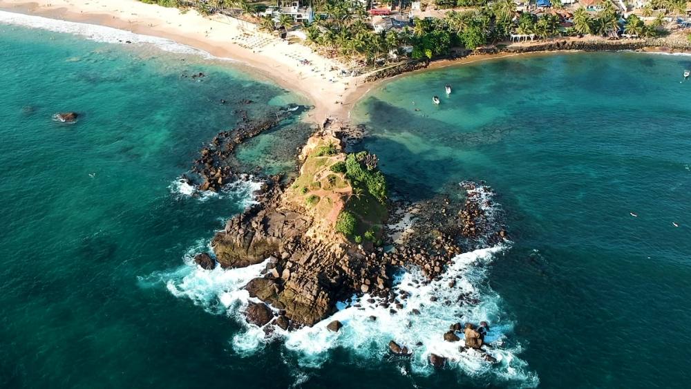 Parrot Rock at Mirissa, ringed by turquoise water and surf