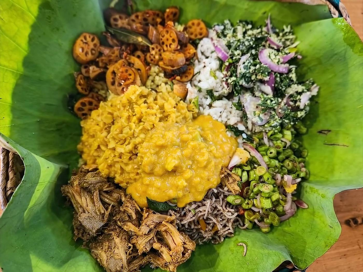A rice and curry spread on a lotus leaf, dhal poured over the top