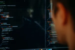Photo of a man looking at a screen with code