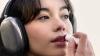 Woman wearing headphones applying a red Mavala tinted lip balm