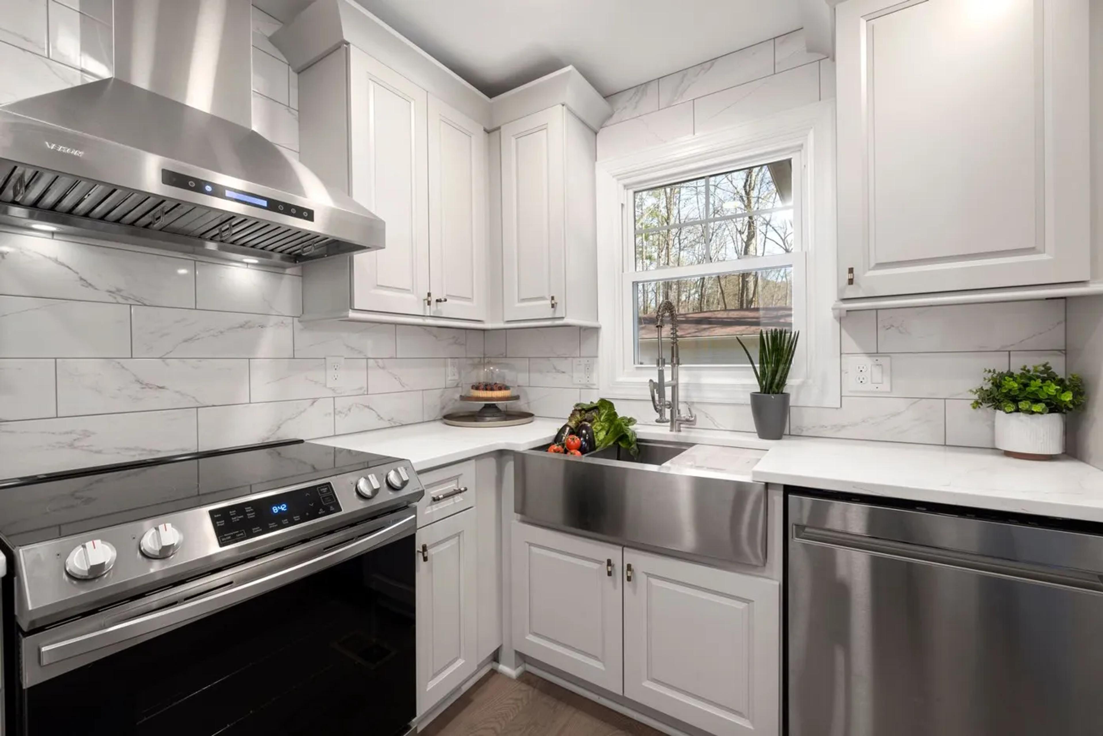 White kitchen with a stainless steel range, range hood, and dishwasher